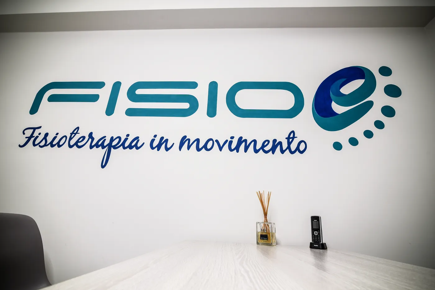 Parete con il logo Fisioe, Fisioterapia in movimento, nello studio di Roma